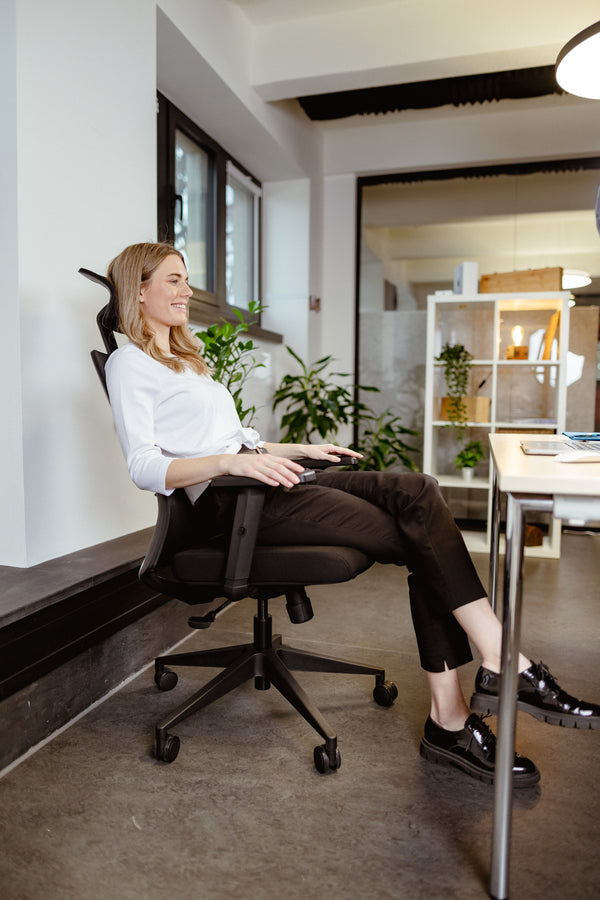 Frau sitzt im VALKENSTOL M3 Bürostuhl am Schreibtisch im hellen Büro